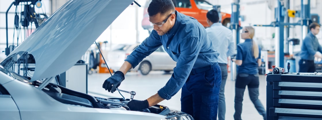Auto worker looking under the hood at repair shop